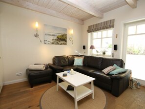 A cozy living room with a leather sofa, a white coffee table, and a painting on the wall. - Seeschwalbe at Susanne-fischer-weg 49 (Wyk auf Foehr)