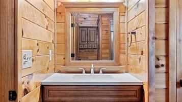 A wooden cabin bathroom with a central sink, a mirror, and cabinets.