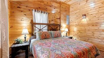 A wooden-paneled room with a bed, two bedside tables, and a nightstand.