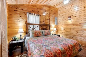 Habitació amb panells de fusta, un llit, dues taules de nit i un taulell.