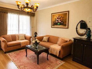 A living room with two sofas, a coffee table, a chandelier, a painting, and a cabinet. - B7 Group 72  (Cairo Governorate)