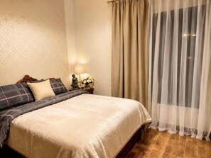 A hotel room with a bed, a nightstand with a lamp, and a window with curtains. - B7 Group 72  (Cairo Governorate)
