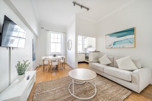 Ein modernes Wohnzimmer mit Sofa, Couchtisch und einem Essbereich mit Tisch und Stühlen.