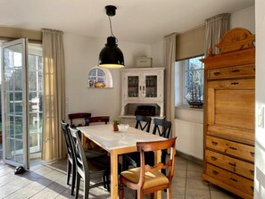 Ein Essbereich mit Tisch, Stühlen, einem Schrank und einem Fenster mit Vorhängen.