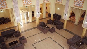 A spacious lobby with multiple seating areas, a central open space, and decorative columns. - Offra Douz  (Ghlissia)