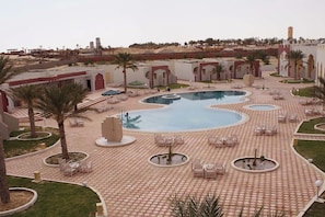 A pool area with multiple circular pools, lounge chairs, and palm trees.