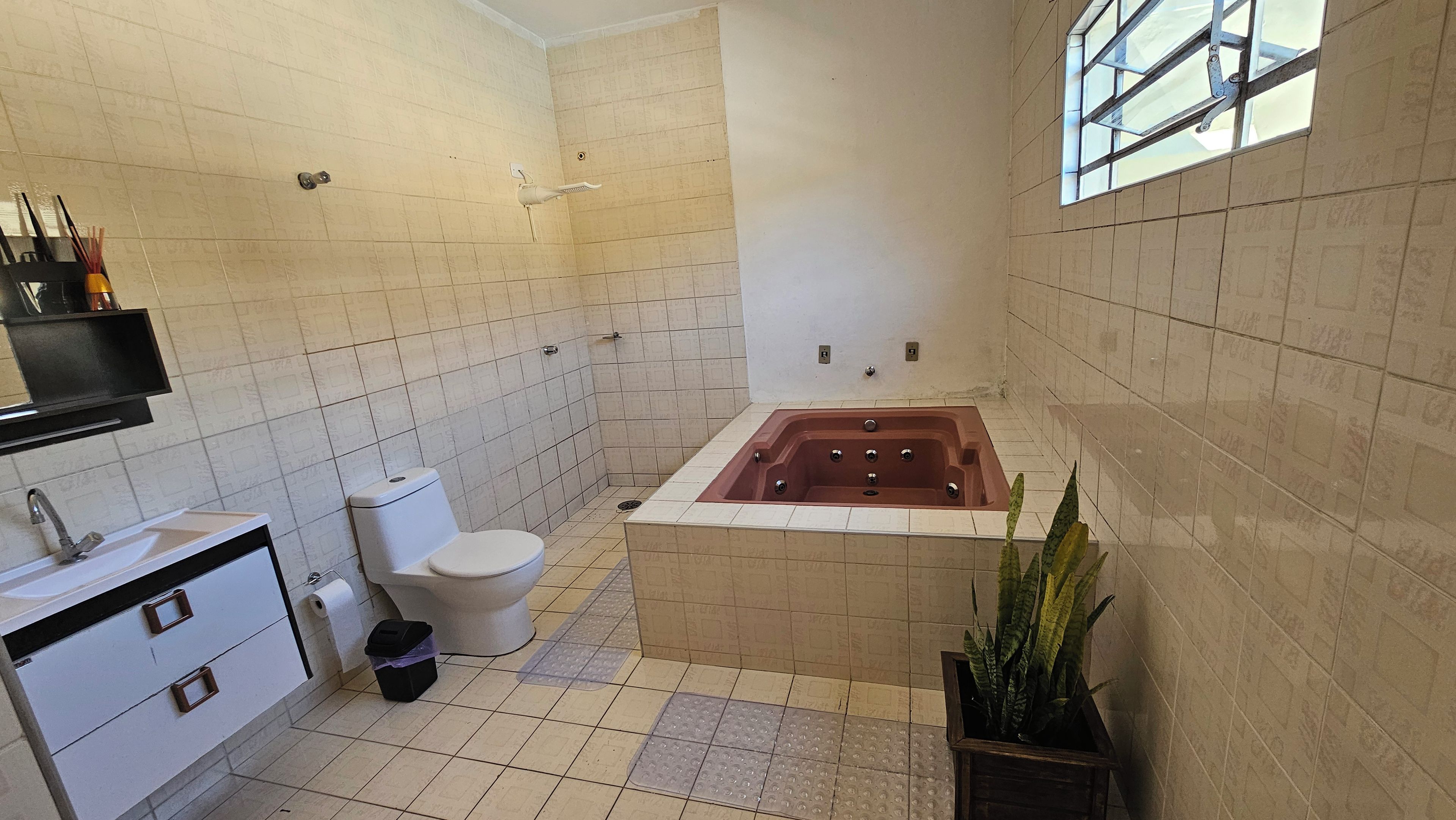 A bathroom with a bathtub, toilet, sink, and a potted plant.