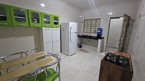 A kitchen with white cabinets, a green table, and a gas stove. - House for 6. Private pool | Hot tub (Pindamonhangaba)