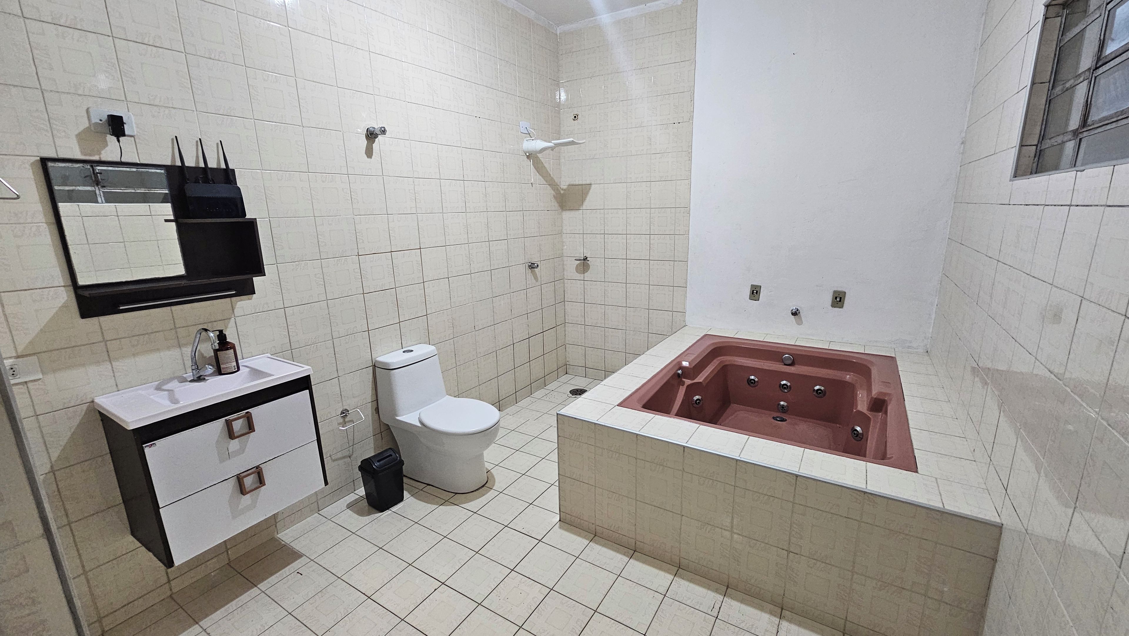 Een badkamer met een wit toilet, een wastafel met spiegel en een bad.