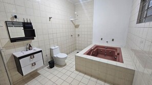 Een badkamer met een wit toilet, een wastafel met spiegel en een bad.