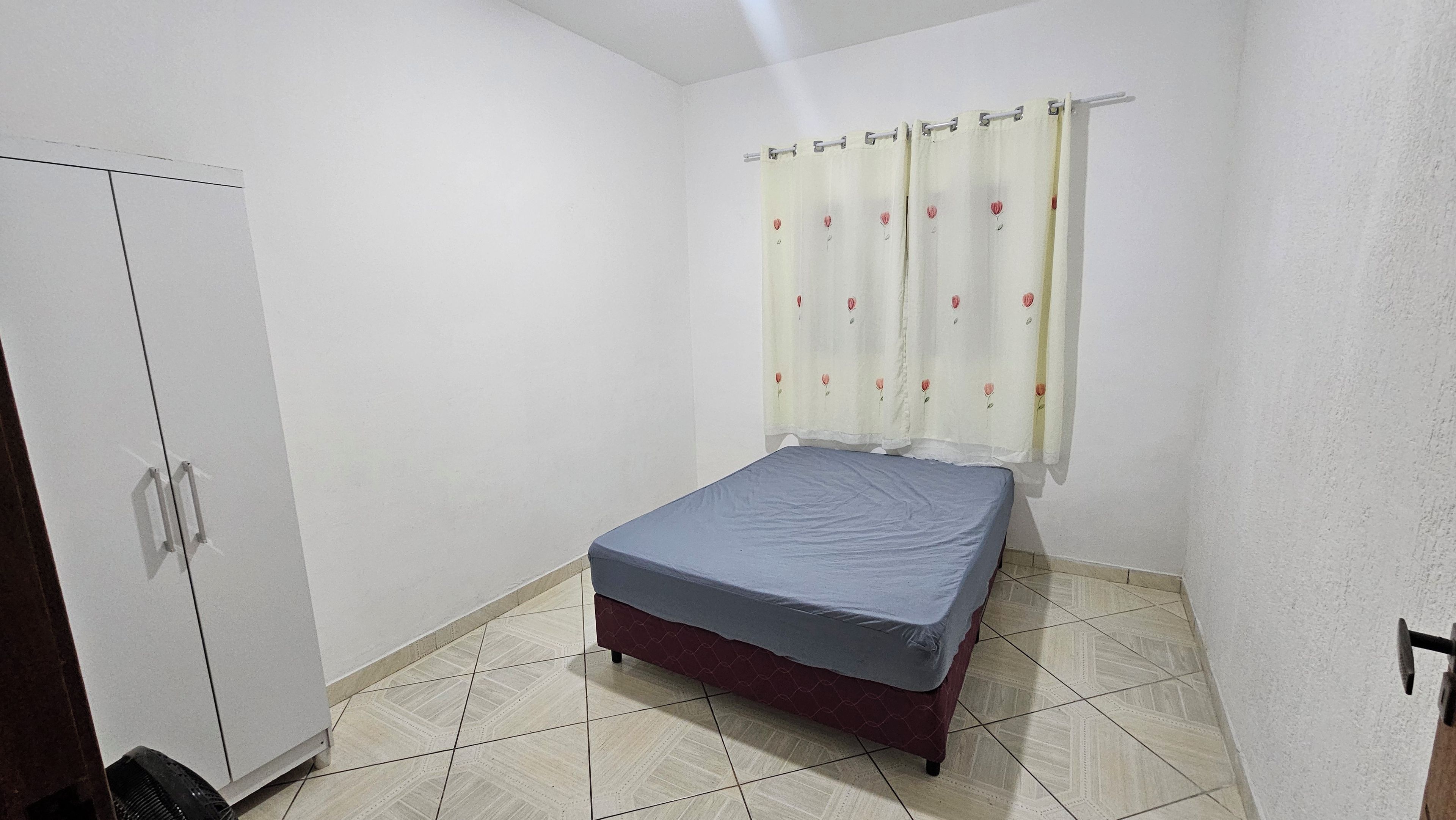 Een slaapkamer met een bed, een kledingkast en een gordijn.
