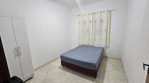 Een slaapkamer met een bed, een kledingkast en een gordijn.