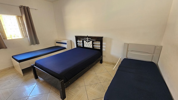 A room with two single beds, a desk, and a window with curtains.