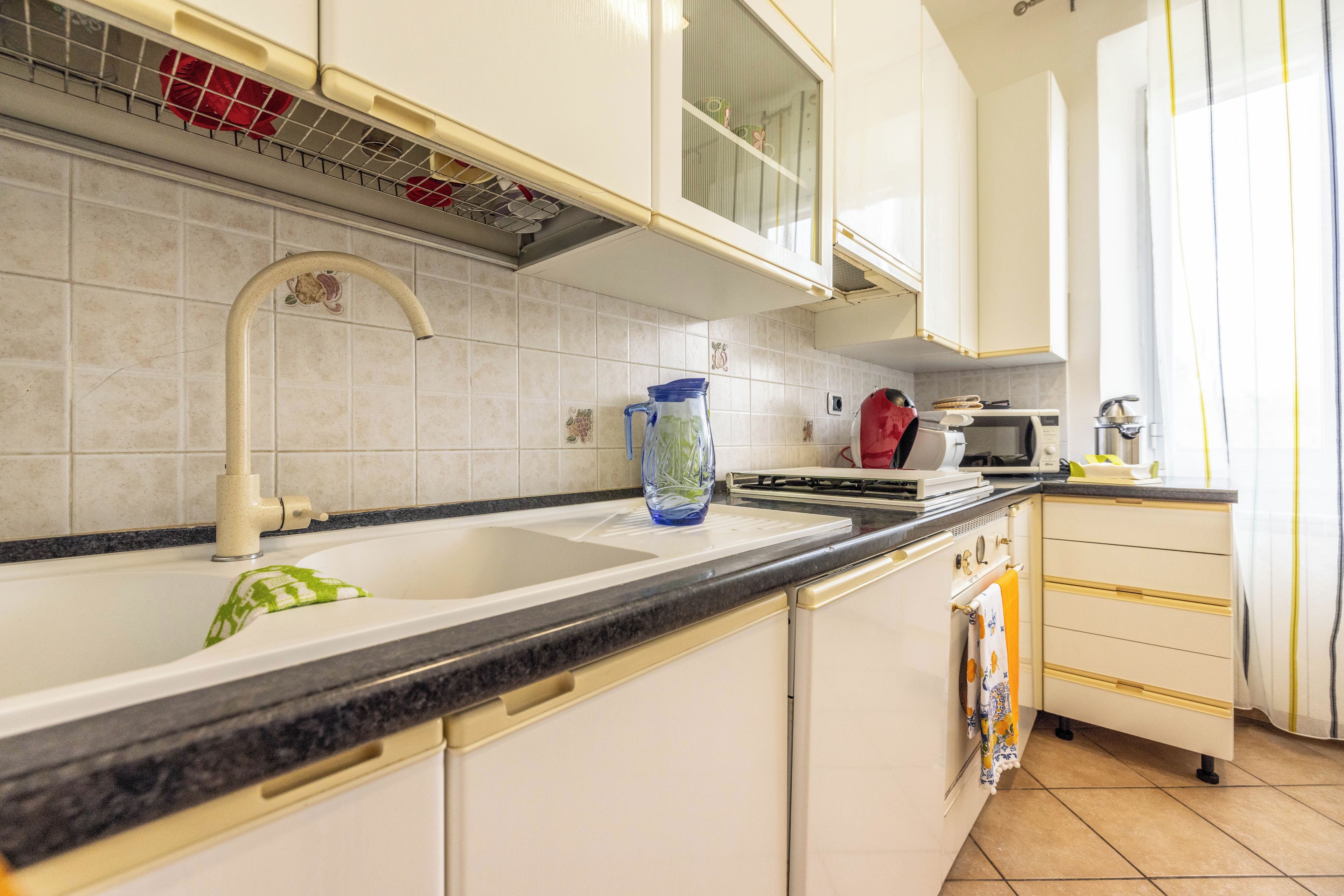 A kitchen with a sink, faucet, and a microwave.
