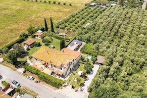 A large house with a tiled roof, surrounded by a well-maintained garden and a vineyard. - Villa Querciolo (Toscana)