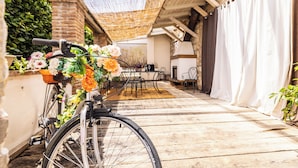 Ein Fahrrad mit befestigten Blumen am Lenker, abgestellt auf einer Holzterrasse.