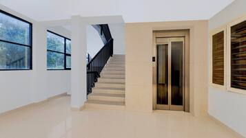A modern interior with a staircase, elevator, and large windows.
