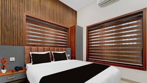 A modern hotel room with a large bed, wooden headboard, and a view through wooden blinds. - Townhouse Oak Thondayad Calicut Dream (Calicut)