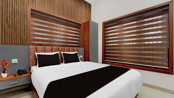 Una habitación de hotel moderna con una cama grande, cabecera de madera y vistas a través de persianas de madera.
