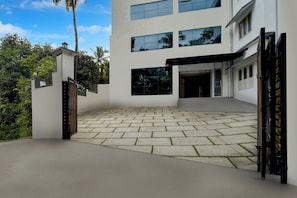 Un edificio moderno de dos pisos con un camino de entrada pavimentado y un acceso con portón.