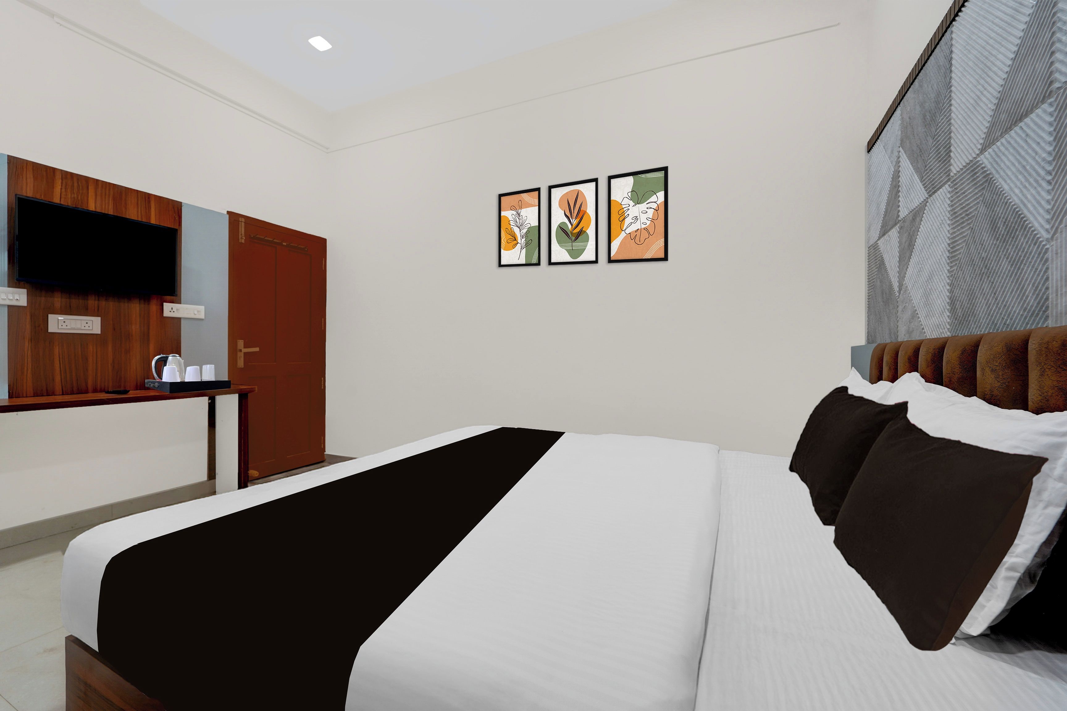Une chambre d’hôtel comprenant un lit, un bureau, une armoire et trois œuvres d’art encadrées accrochées au mur.