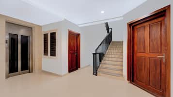 Un pasillo con una escalera, un ascensor y puertas de madera.