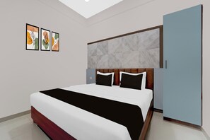 Une chambre à coucher moderne avec un grand lit, une tête de lit ornée d’un motif géométrique et trois œuvres d’art encadrées accrochées au mur.
