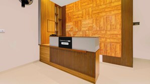 A reception desk with a sign indicating it is company-serviced, a wall with a geometric wood pattern, and a door with a number sign. - Townhouse Oak Thondayad Calicut Dream (Calicut)