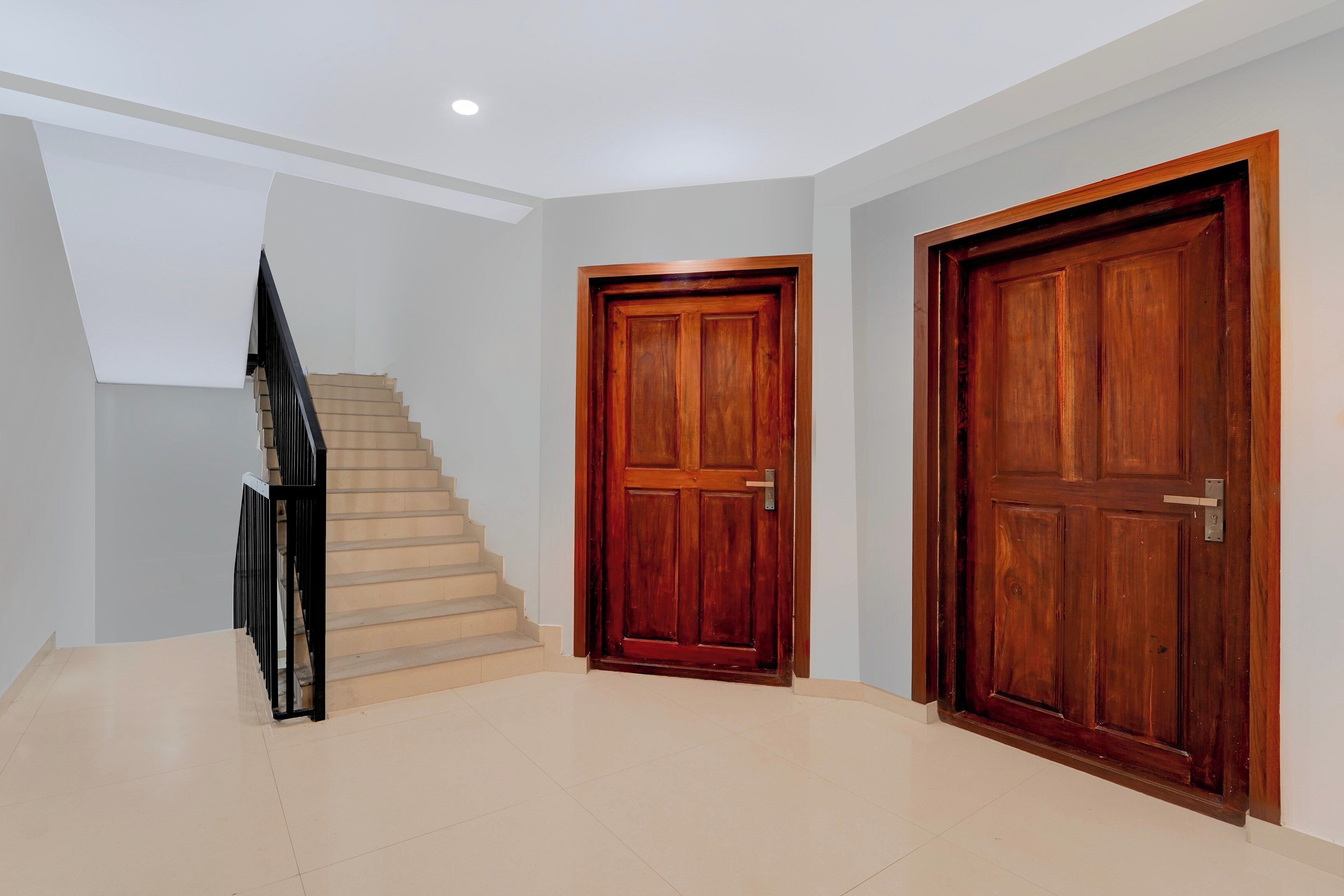 Un interior moderno con una escalera, dos puertas de madera y una luz empotrada en el techo.