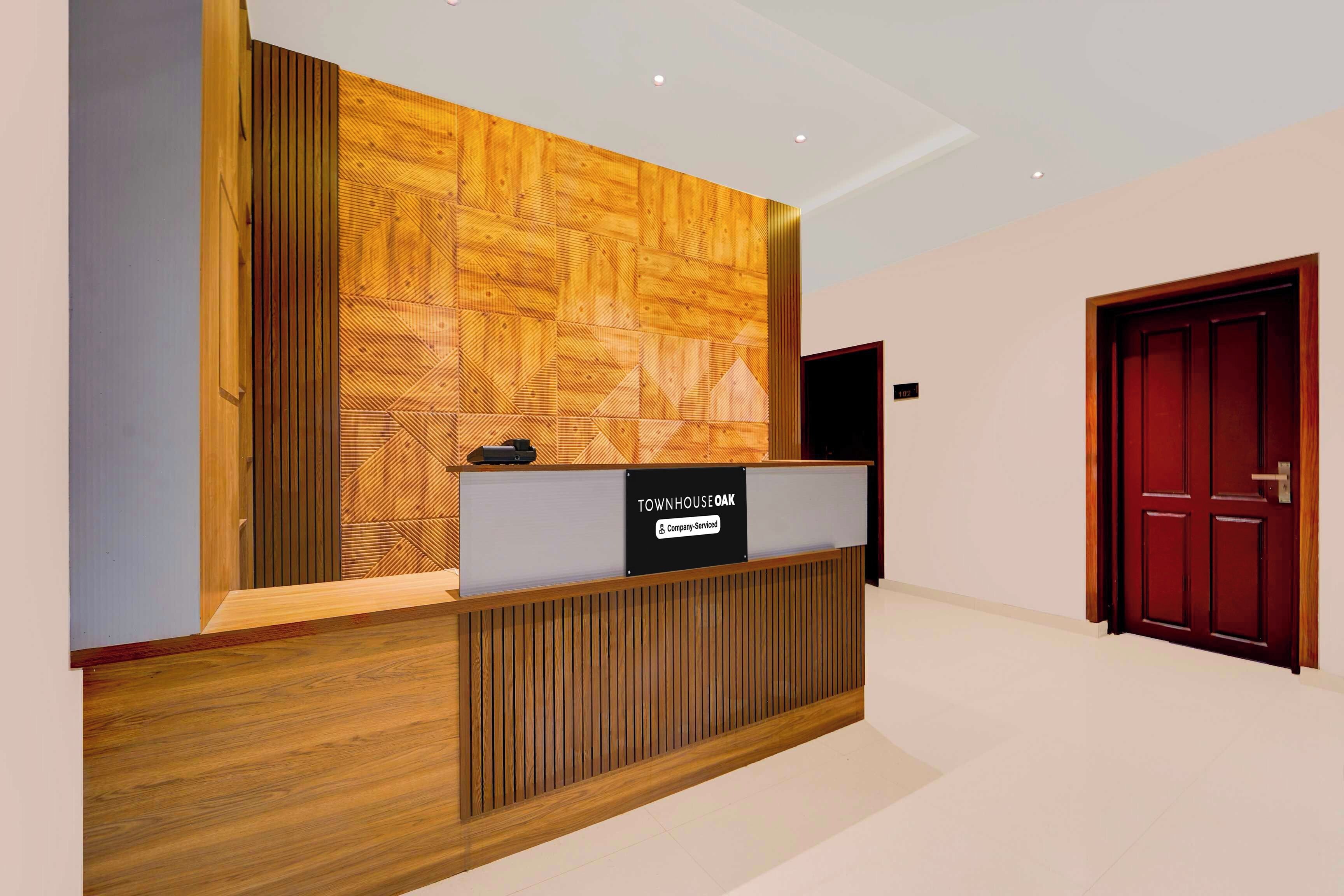 A reception desk with a company-serviced sign, a wooden panel wall, and a red door in the background.