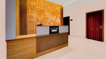 A reception desk with a company-serviced sign, a wooden panel wall, and a red door in the background.
