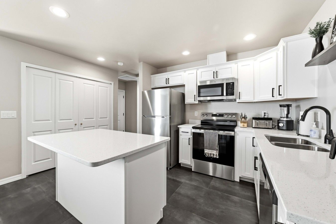 A modern kitchen with white cabinetry, stainless steel appliances, and a central island.
