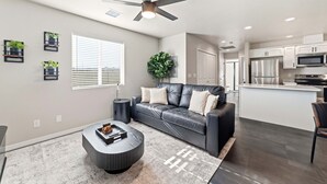 A modern living room with a leather sofa, a coffee table, and a ceiling fan. - Work-Ready Stay with Desk + ALLO Fiber WiFi (Kingman)