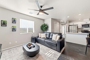A modern living room with a leather sofa, a coffee table, and a ceiling fan. - Work-Ready Stay with Desk + ALLO Fiber WiFi (Kingman)