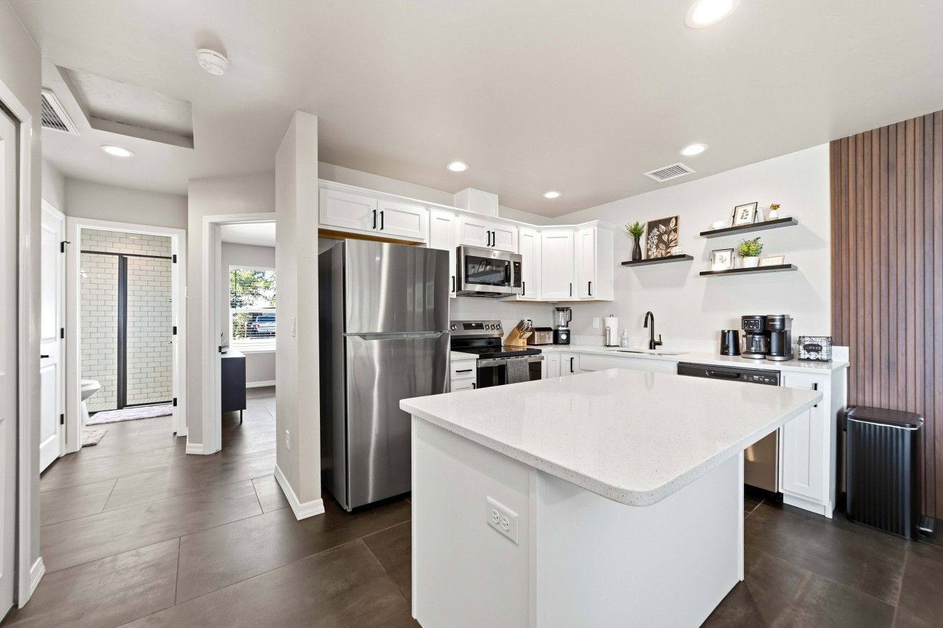 A modern kitchen with white cabinetry, stainless steel appliances, and a central island.