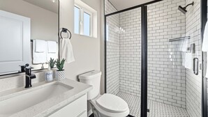 A modern bathroom with a shower, toilet, sink, and a large mirror. - Work-Ready Stay with Desk + ALLO Fiber WiFi (Kingman)
