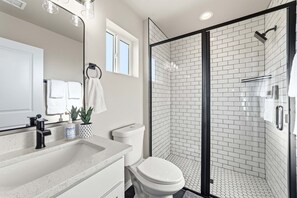 A modern bathroom with a shower, toilet, sink, and a large mirror. - Work-Ready Stay with Desk + ALLO Fiber WiFi (Kingman)