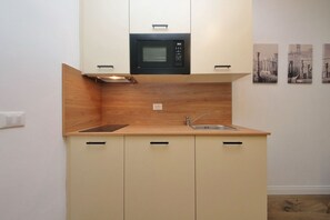 A compact kitchen with a microwave, sink, and wooden backsplash. - Urbana - Modern apartment for 4 close to the Coloseum (Roma)