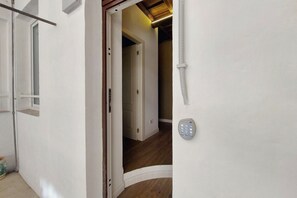 A hallway with a door leading to another room, a wall-mounted intercom, and a wooden floor. - Urbana - Modern apartment for 4 close to the Coloseum (Roma)