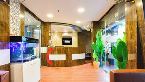 Un espace d’accueil avec un comptoir de réception en bois, un aquarium et un panneau indiquant « TOWNHOUSE & Company – Services inclus ».