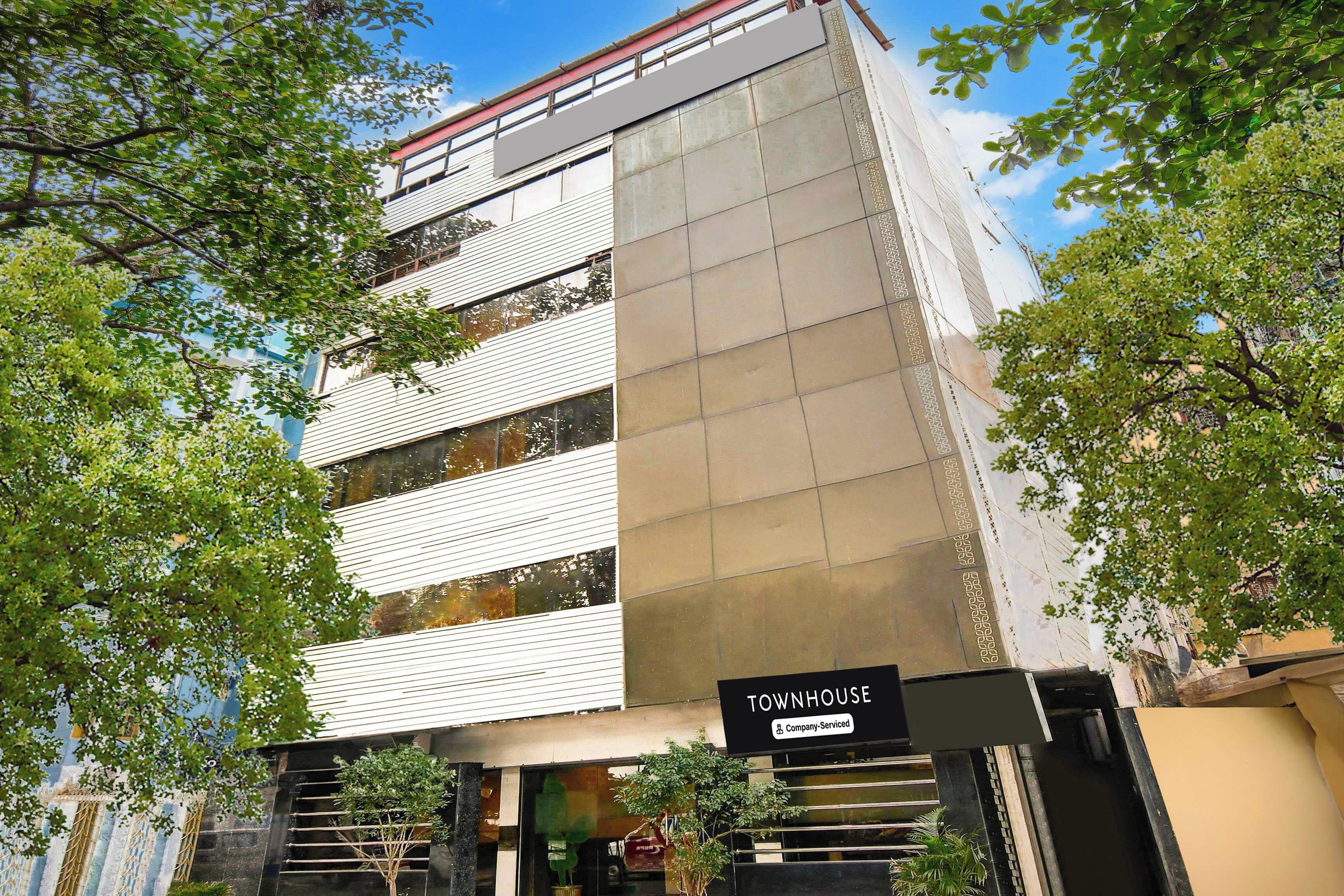 Una casa adosada moderna con un cartel de la empresa, ventanas amplias y una escalera que lleva a la entrada.