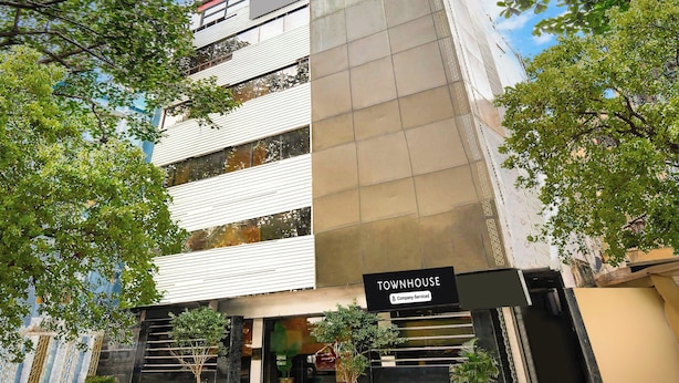 Une maison de ville moderne dotée d’une enseigne entretenue par l’entreprise, de grandes fenêtres et d’un escalier menant à l’entrée.