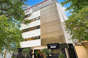 Uma casa geminada moderna com placa de serviço da empresa, janelas amplas e escadaria que leva à entrada.