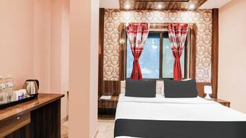 Habitación de hotel con una cama, una mesita de noche con tetera, una mesita de noche y una ventana con cortinas.