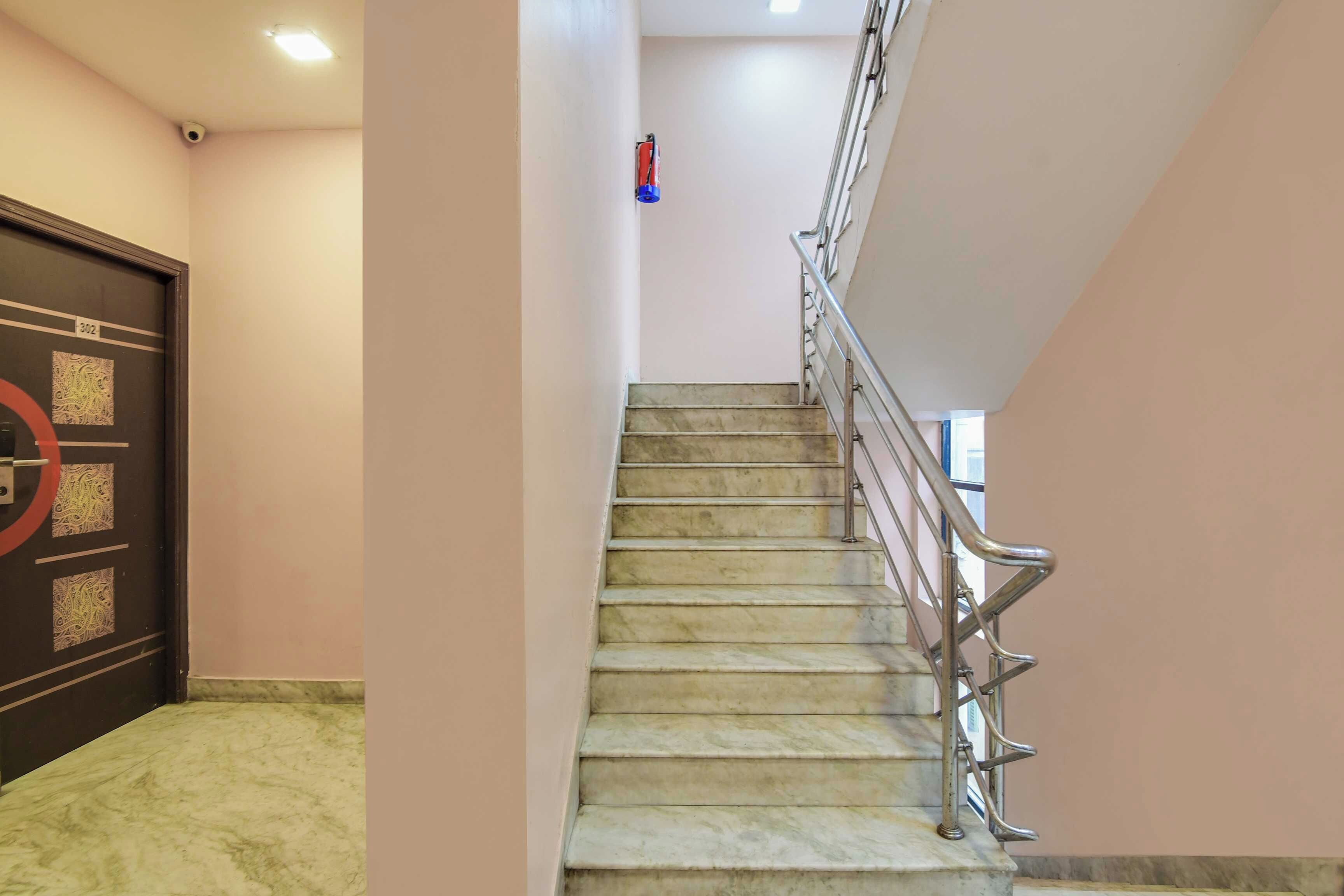 A staircase with marble steps, metal handrails, and a door with a circular design.