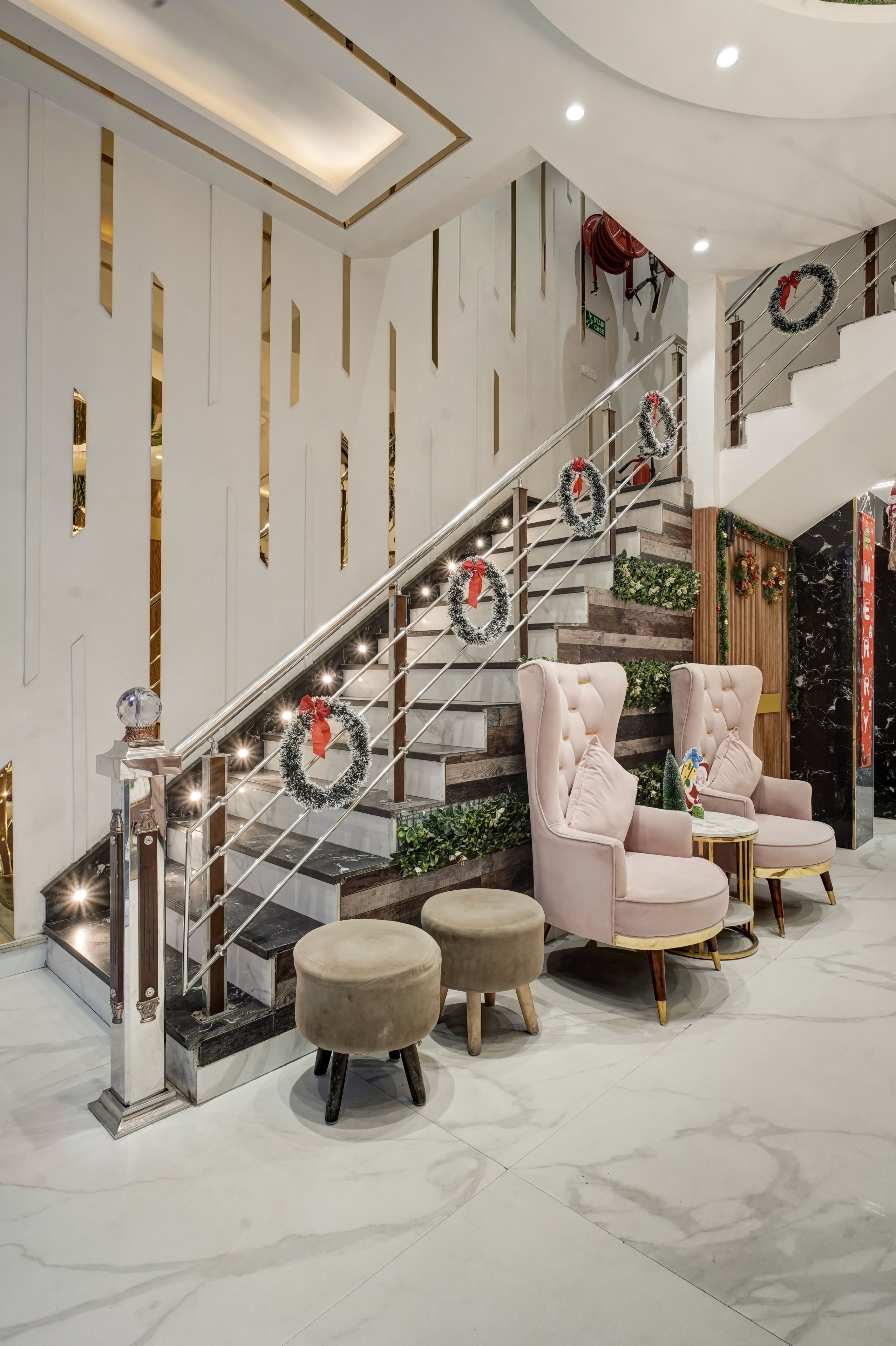 Un escalier orné de guirlandes décoratives, un fauteuil moelleux et un petit pouf.