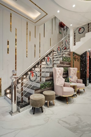Un escalier orné de guirlandes décoratives, un fauteuil moelleux et un petit pouf.