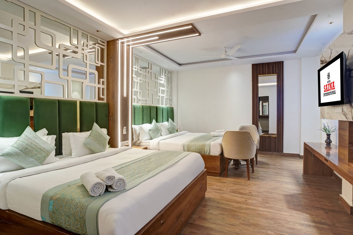 A hotel room with two beds, a desk, a chair, and a television.