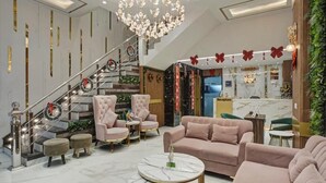 Een moderne hotellobby met een trap, comfortabele zithoeken en een receptiebalie.