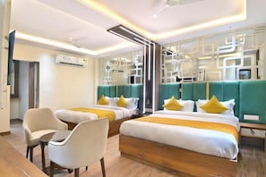 Habitación de hotel con dos camas, zona de estar y decoración en la pared.
